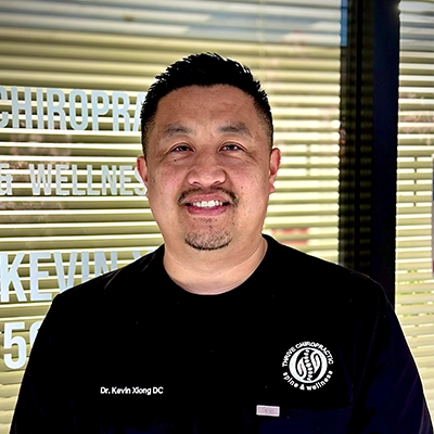 Chiropractor Kevin Xiong Smiling In Scrubs