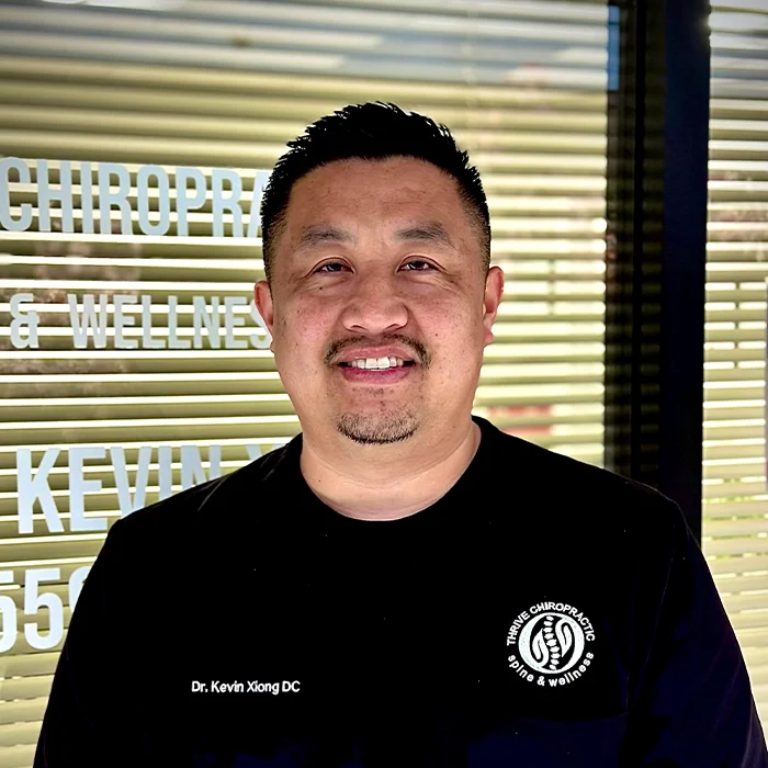 Chiropractor Kevin Xiong Smiling In Scrubs Outside Office
